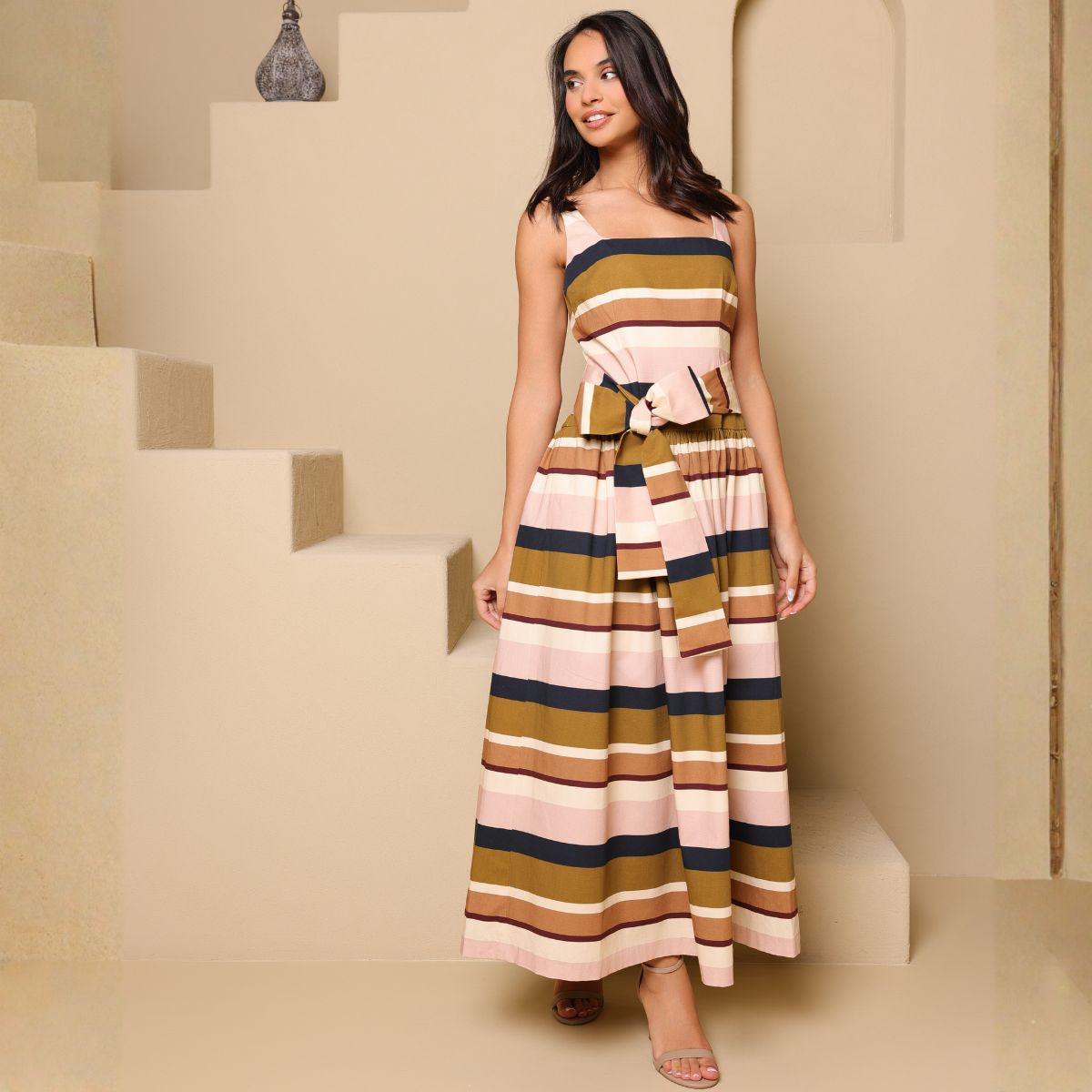 Woman wearing a striped dress standing on a staircase with a neutral background